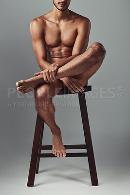 Buy stock photo Studio shot of a handsome young man sitting on a chair in the nude against a grey background