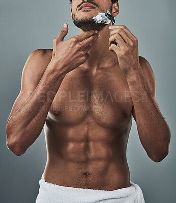 Buy stock photo Studio shot of a handsome and shirtless young man shaving his beard against a grey background