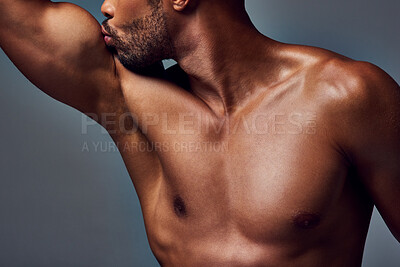 Buy stock photo Studio shot of a muscular young man kissing his bicep while posing shirtless against a grey background
