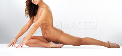 Buy stock photo Studio portrait of a gorgeous young woman doing a split stretch while naked against a grey background