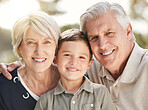 Portrait of loving caucasian grandparents enjoying time with grandson in nature. Smiling little boy bonding with grandmother and grandfather. Happy seniors and child smiling and looking at the camera