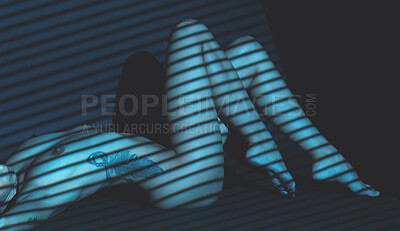 Nude mixed race woman posing while lying on the ground in a dark studio. Sexy hot naked hispanic model showing her body in creative and artistic light. Nudist feeling sensual, seductive and free