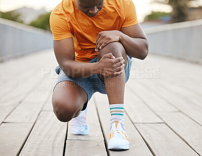 Buy stock photo A jogger with knee pain. An African American man grabbing his knee in pain from exercising