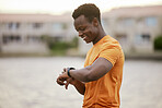A man looking at his watch and smiling. An African America man in sportswear waiting and smiling at his smartwatch.