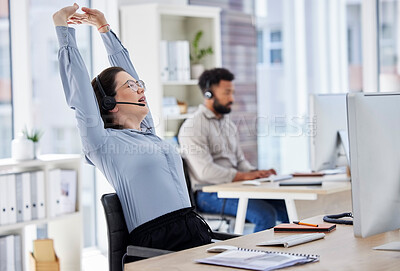 Young caucasian call centre telemarketing agent stretching her arms and yawning while working in an office. Female consultant taking a break after tiring workday of operating helpdesk for customer service and sales support