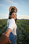 Portrait of a woman in farmer attire holding the hand of her boyfriend while walking in a cabbage field. Unrecognisable person holding hands with a brunette woman on a romantic walk on a farm