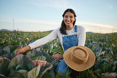 Buy stock photo Portrait of a woman farmer working in a cabbage field. Young brunette female with a straw hat looking at the quality of her organic vegetables