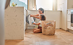 Young hispanic mother and her daughter sorting dirty laundry in the washing machine at home. Adorable little girl and her mother doing chores together at home