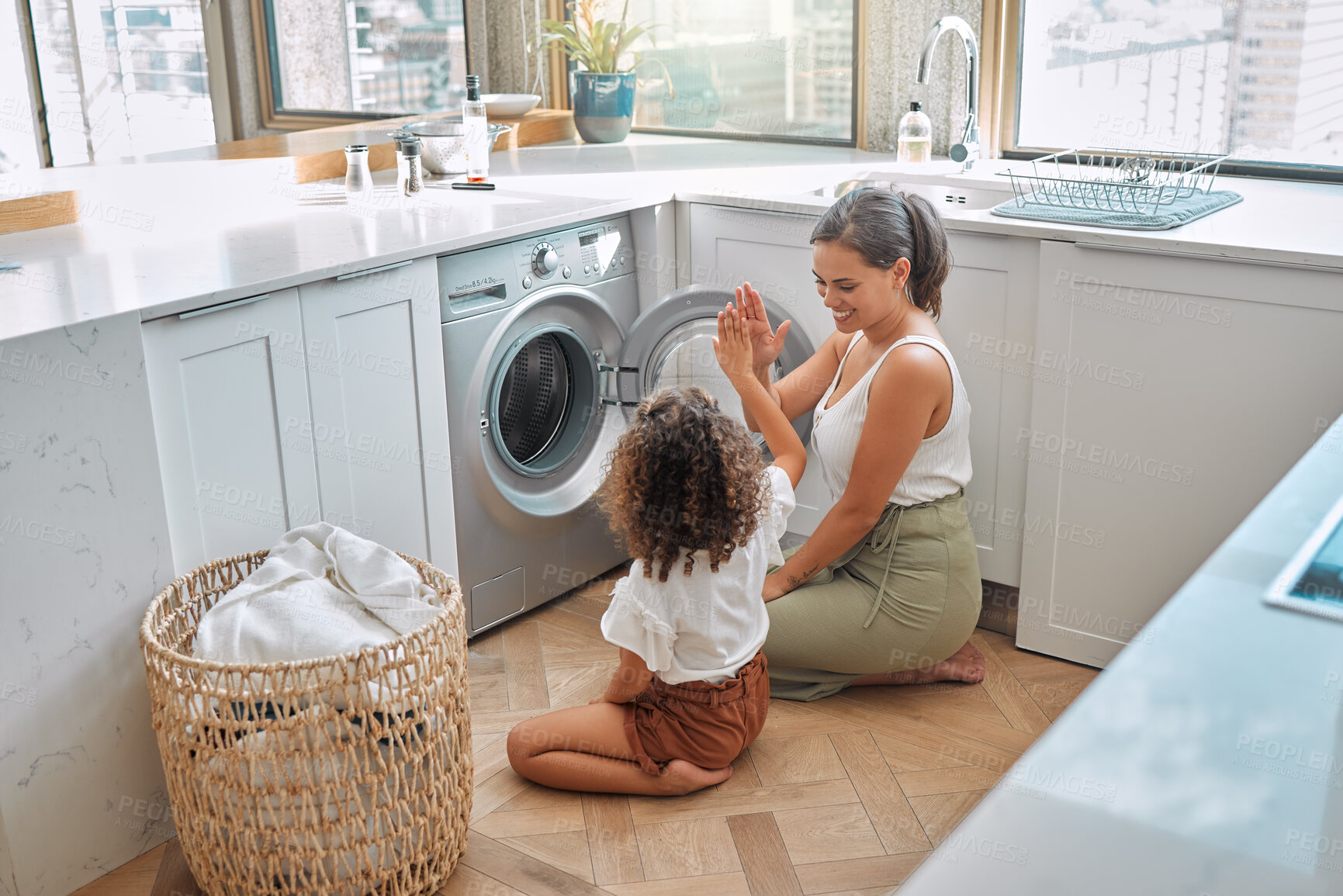 Buy stock photo High five, laundry and washing machine with mother and daughter for helping, learning and cleaning. Housekeeping, teamwork and basket with woman and young girl in family home for teaching and clothes