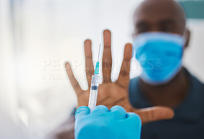 Patient refusing to take covid vaccine. Saying no to corona virus cure. Hand of patient making stop gesture for corona virus vaccine. Doctor holding a needle ready to inject a patient with the cure