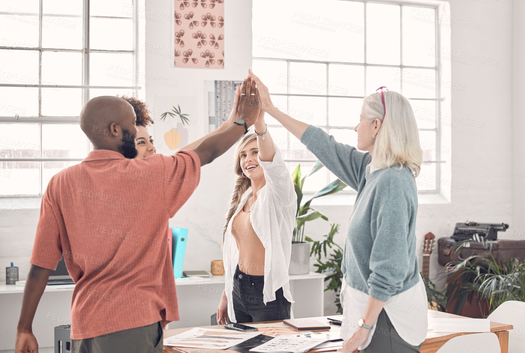 Buy stock photo Group of diverse businesspeople giving each other a high five in an office at work. Business professionals having fun joining their hands for support and motivation during a meeting