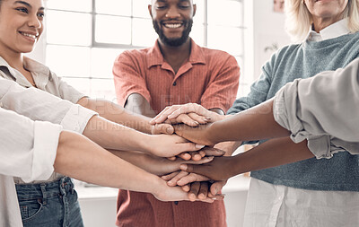 Group of diverse businesspeople piling their hands together in an office at work. Business professionals having fun standing with their hands stacked for motivation and unity