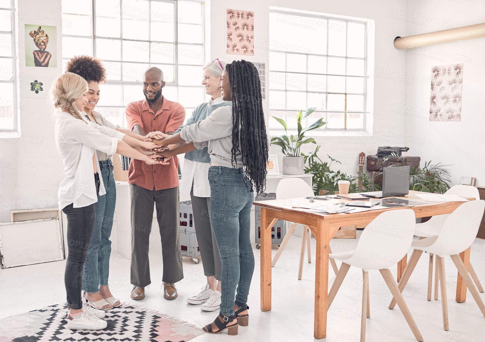 Buy stock photo Fullbody of a group of diverse businesspeople piling their hands together in an office at work. Business professionals having fun standing with their hands stacked for motivation and unity