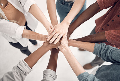Group of diverse businesspeople piling their hands together in an office at work. Business professionals having fun standing with their hands stacked for support and unity from above