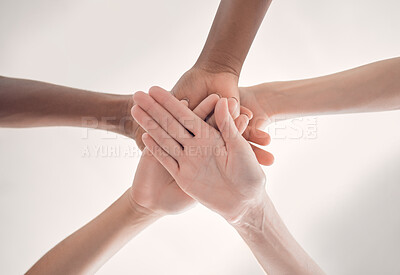 Group of diverse businesspeople piling their hands together in an office at work. Business professionals having fun standing with their hands stacked for support and unity from below