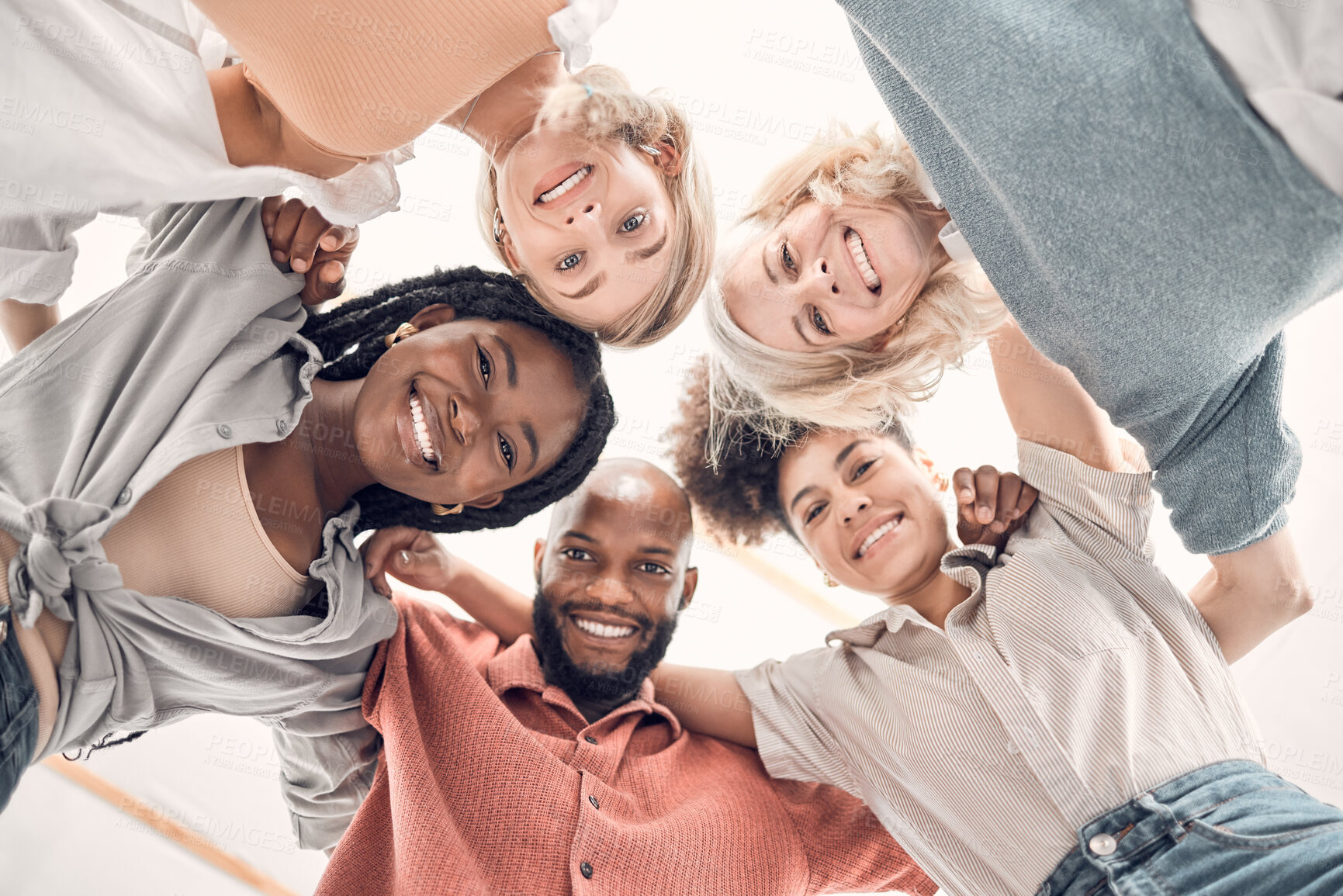 Buy stock photo Low portrait of a group of five cheerful diverse businesspeople standing together in an office at work. Happy business professionals standing at work. Colleagues huddling together in support and motivation