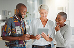 Three happy businesspeople using a digital tablet together at work. Mature caucasian businesswoman talking and showing her african american colleagues an idea of a digital tablet in an office