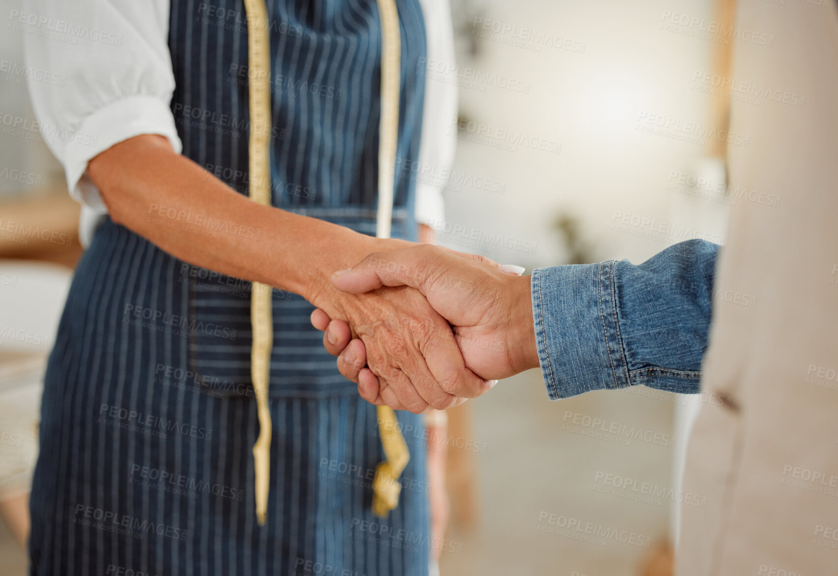 Buy stock photo Two clothing designers shaking hands while working together at a shop. Tailors giving each other a handshake at work. Colleagues greeting at work. Business partners making a deal with a handshake
