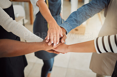 Group of clothing designers stacking their hands together in a shop at work. Tailors having fun standing with their hands piled for support and motivation during a meeting at a boutique from above