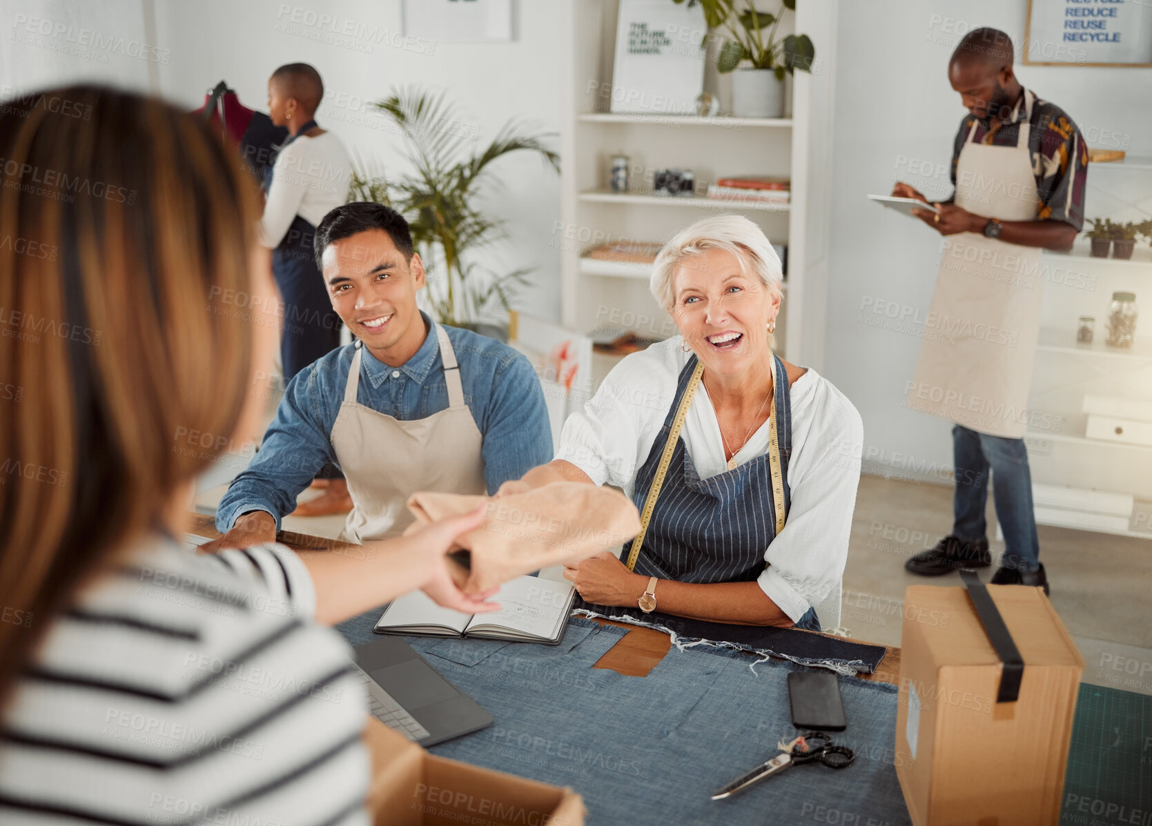 Buy stock photo Joyful mature caucasian clothing designer talking and giving a customer a package in a shop at work. Customer making a purchase from a female clothing designer at a boutique