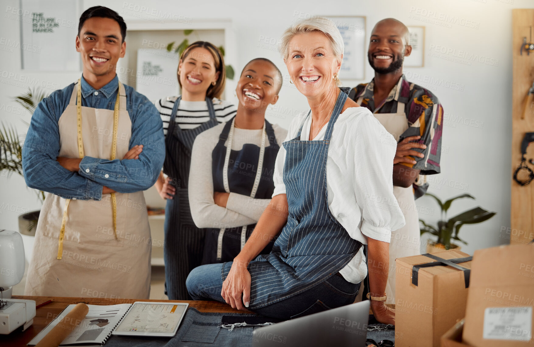 Buy stock photo Group of five cheerful diverse clothing designers standing with their arms crossed in a shop at work. Joyful tailors smiling and laughing while standing together in a boutique. Mature caucasian boss standing with her employees