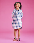 A portrait of a pretty little mixed race girl with curly hair posing against a pink copyspace background in a studio. A smiling African child wearing casual clothes indoors