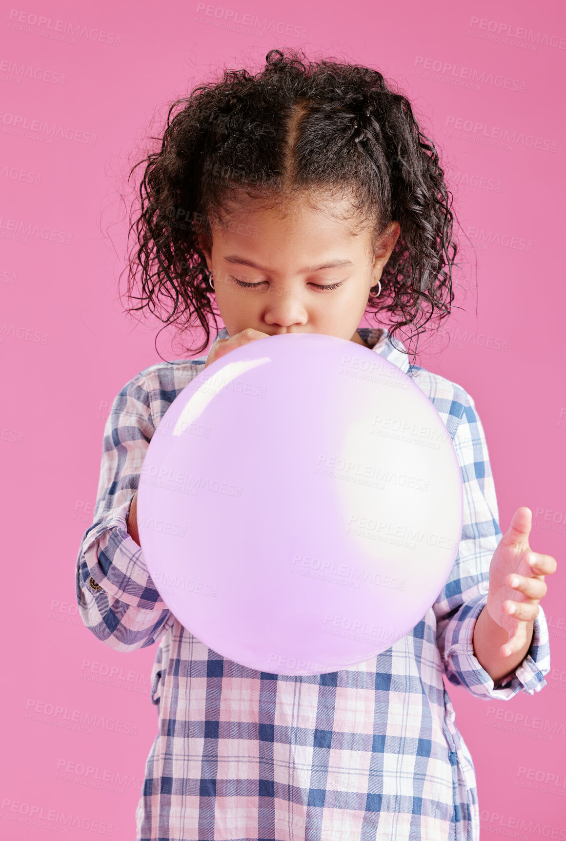 Buy stock photo A pretty little mixed race girl with curly hair blowing a balloon against a pink copyspace background in a studio. African child looking content while having fun