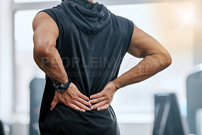 Unknown trainer alone in gym and suffering from back injury. Coach standing and rubbing back during workout in exercise health club. One man in fitness centre feeling backache pain in routine training