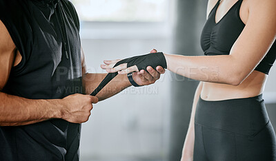 Unknown mixed race trainer wrapping caucasian boxer’s hands in gym. Hispanic coach getting kickboxer ready to fight in self defence in health club workout. Woman in fitness centre in training exercise