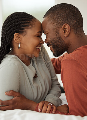 Buy stock photo Close up of a loving african american couple touching foreheads while lying together on a bed. Happy young man and woman sharing romantic intimate moment at home