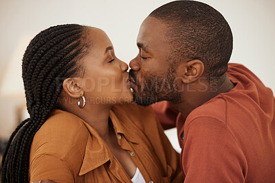 Close up of a loving african american couple sharing a passionate kiss while lying together on a bed. Happy young man and woman sharing romantic intimate moment at home