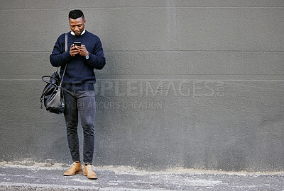 Businessman using his cellphone while walking in the city. Man using cellphone while commuting to work. Using internet while walking outside. Man using internet while commuting