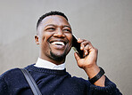 African american male on a phone call with his mobile device outside a building during the day while smiling Young black male talking on a phone while commuting to work