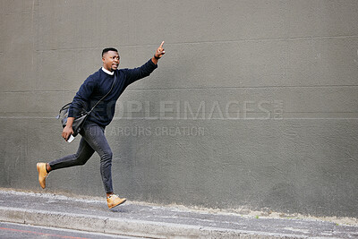 African american businessman travelling alone and rushing for a taxi in the city. Black male running and waving for a taxi while on his way to work in the morning