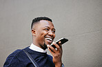 African american male on a phone call with his mobile device outside a building during the day while smiling Young black male talking on a phone while commuting to work