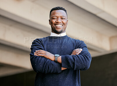 Portrait of a young businessman standing with arms crossed in the street in the city smiling and looking happy on a sunny day. African american male expressing happiness on his face