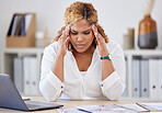Young mixed race businesswoman suffering from a headache while sitting at a desk in an office at work. One stressed hispanic businessperson suffering from anxiety and looking upset