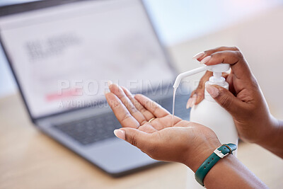 Businessperson holding a bottle and using hand sanitiser while working in an office. Business professional using sanitiser to protect from disease and infection. Person cleaning their hands with sanitiser at work