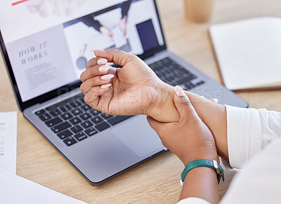 Closeup of a businessperson holding their wrist in pain while sitting at a desk at work. Business professional touching their sore arm while working in an office. Person suffering from arthritis in an office