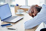Young african american businessman sleeping at his desk at work. Tired male businessperson using a laptop while and napping on a break at work