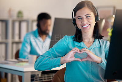 Portrait of one happy young smiling caucasian call centre telemarketing agent gesturing heart shape with her hands while talking on headset in office. Confident friendly businesswoman operating helpdesk for customer care and sales support