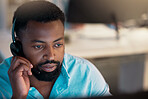 One young african american call centre telemarketing agent talking on a headset while working in an office. Face of focused businessman consultant operating a helpdesk for customer service support