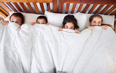 Buy stock photo Above view of happy young caucasian family with two children lying in bed and pulling blanket over their noses. Two parents with daughter and son spending time and having a lazy morning peeking from under white comforter