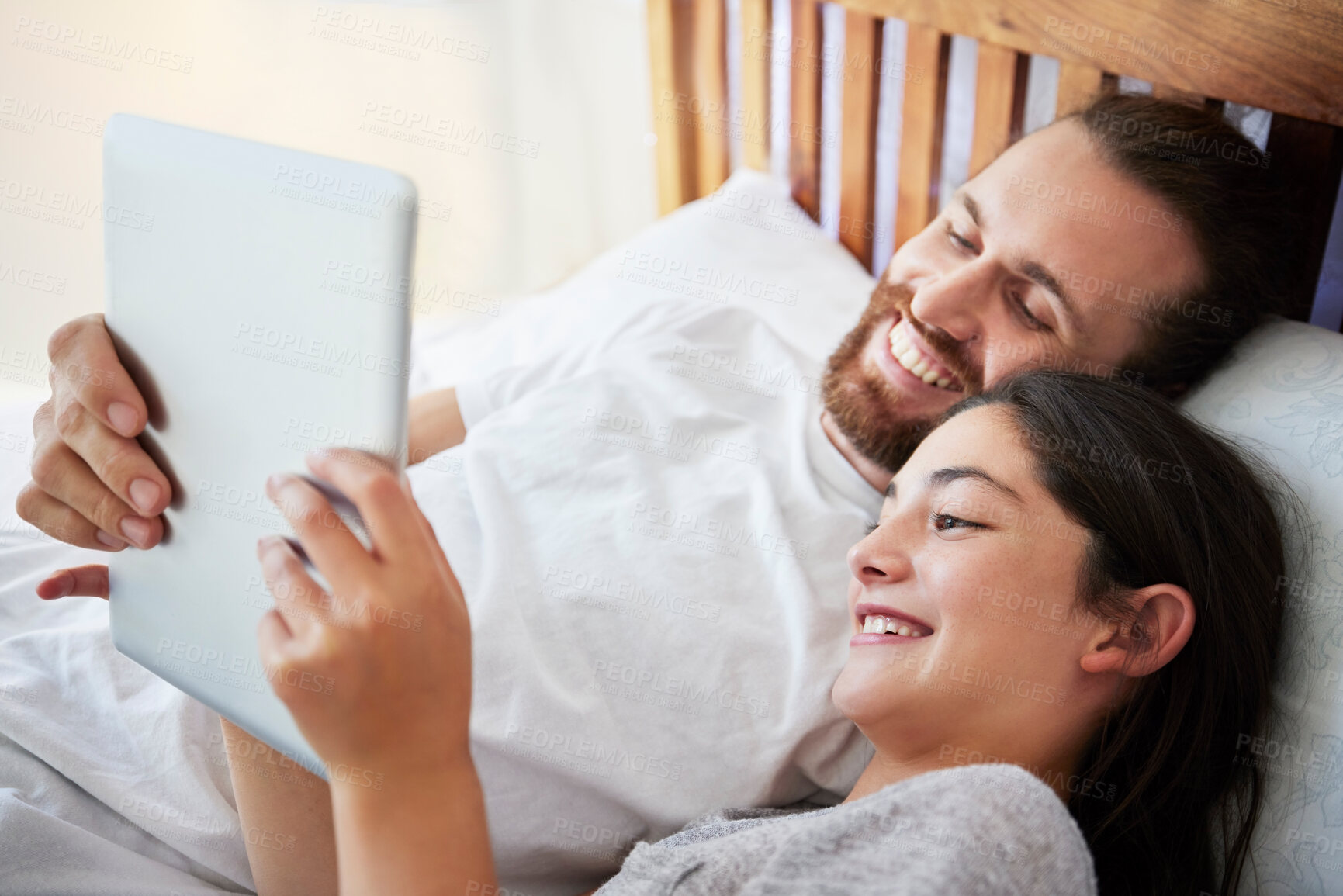 Buy stock photo Happy caucasian father and daughter holding digital tablet while lying together on a bed. Teenage girl and dad watching movie online or playing game while spending time at home
