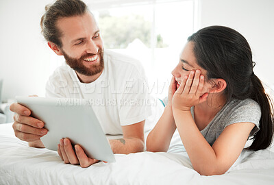Buy stock photo Happy caucasian father and daughter looking at each other while holding digital tablet and lying together on a bed. Young child and dad watching movie online or playing game while spending time at home learning online