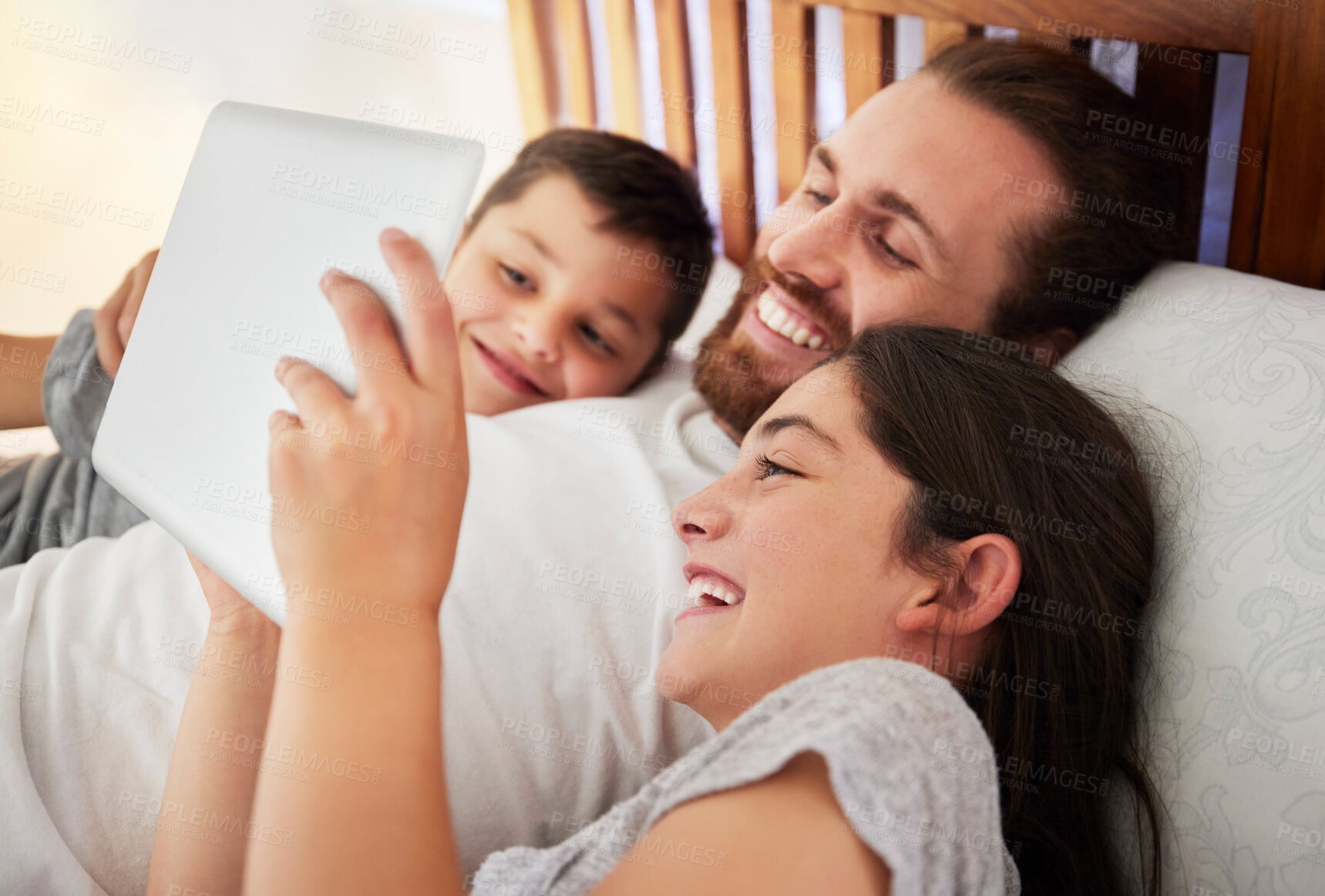Buy stock photo Happy caucasian father lying in bed with his two children using digital tablet and watching movie, reading online book or playing games together at home. Young dad spending time with his daughter and son on the weekend