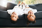 Portrait of two little mixed race siblings spending time together lying upside down at home. Cute hispanic girl and boy playing on the couch in the lounge