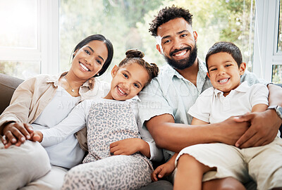 Portrait of a young hispanic family happily bonding together on the sofa at home. Mixed race mother and father sitting of the couch in the loung and looking happy while bonding with their cute little son and daughter
