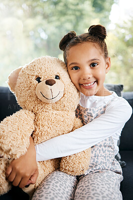 Buy stock photo Portrait of an adorable little hispanic girl holding a teddy bear at home. Cute mixed race girl playing with her toy while sitting on the couch in the lounge