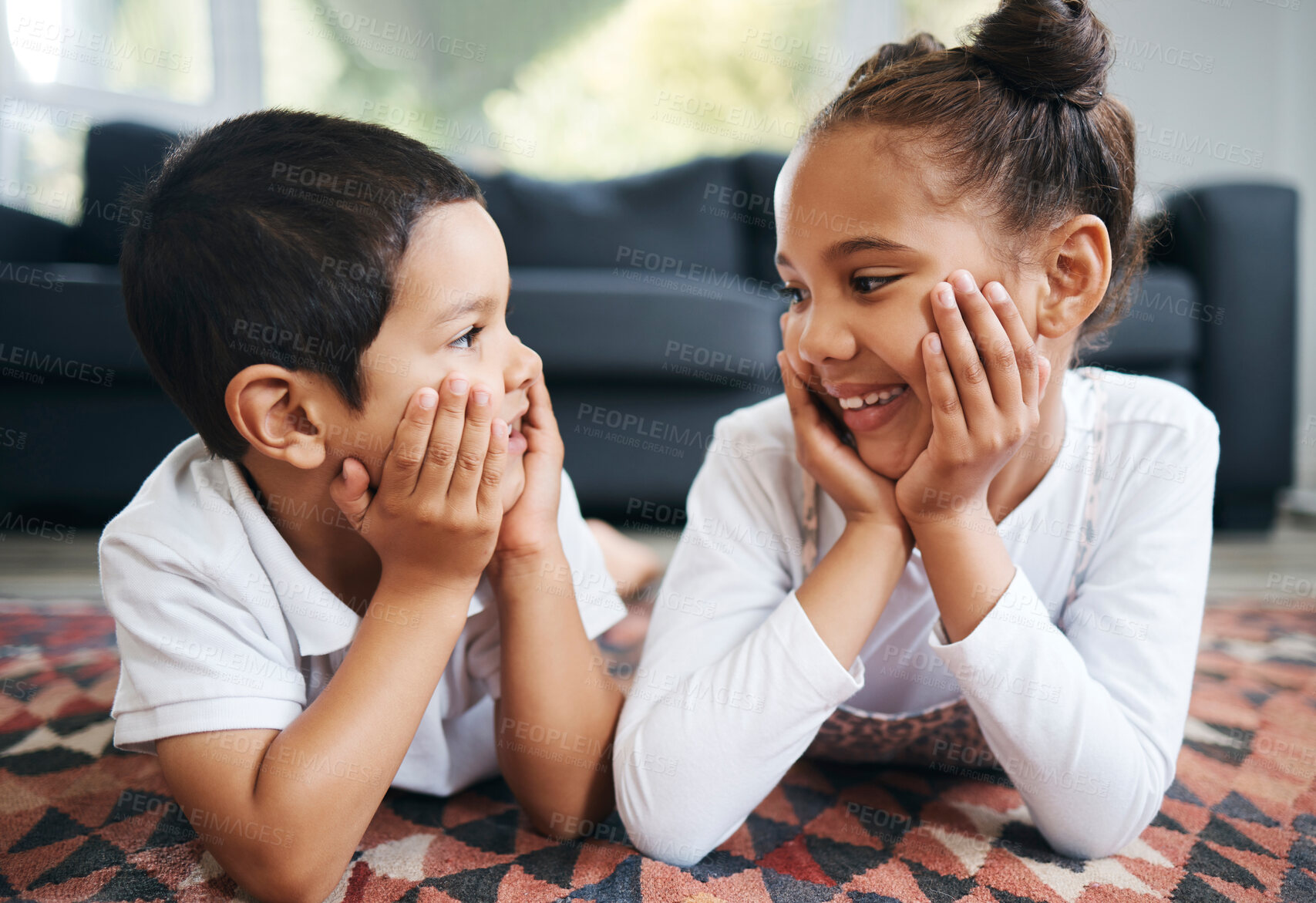 Buy stock photo Closeup of two mixed race young siblings lying on the floor together at home and smiling. Little hispanic boy and girl having fun in the lounge at home